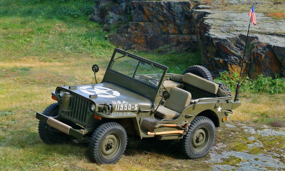 Vintage USA Jeep standing in a natural area covered with grass and backed by a craggy rock formation